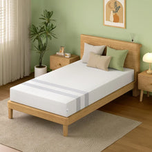 Minimalist bedroom with a wooden bed frame, white mattress with gray stripes, beige and green pillows, green wall, and plant
